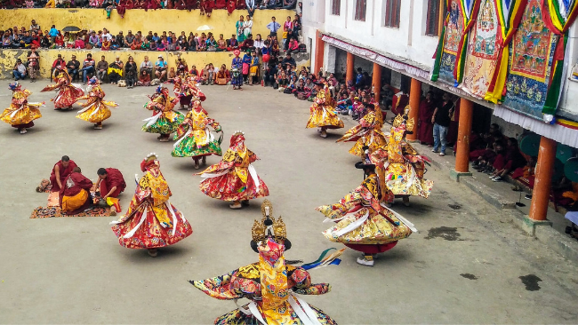 Author looks at the Key Monastery from the parking as white, yellow and red flags flutter in air at the Ki Monastery in Spiti