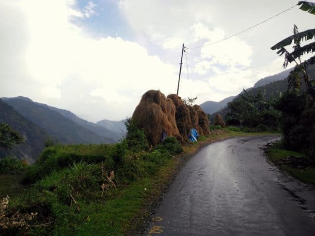 hay stacks kept on the side of a hilly road