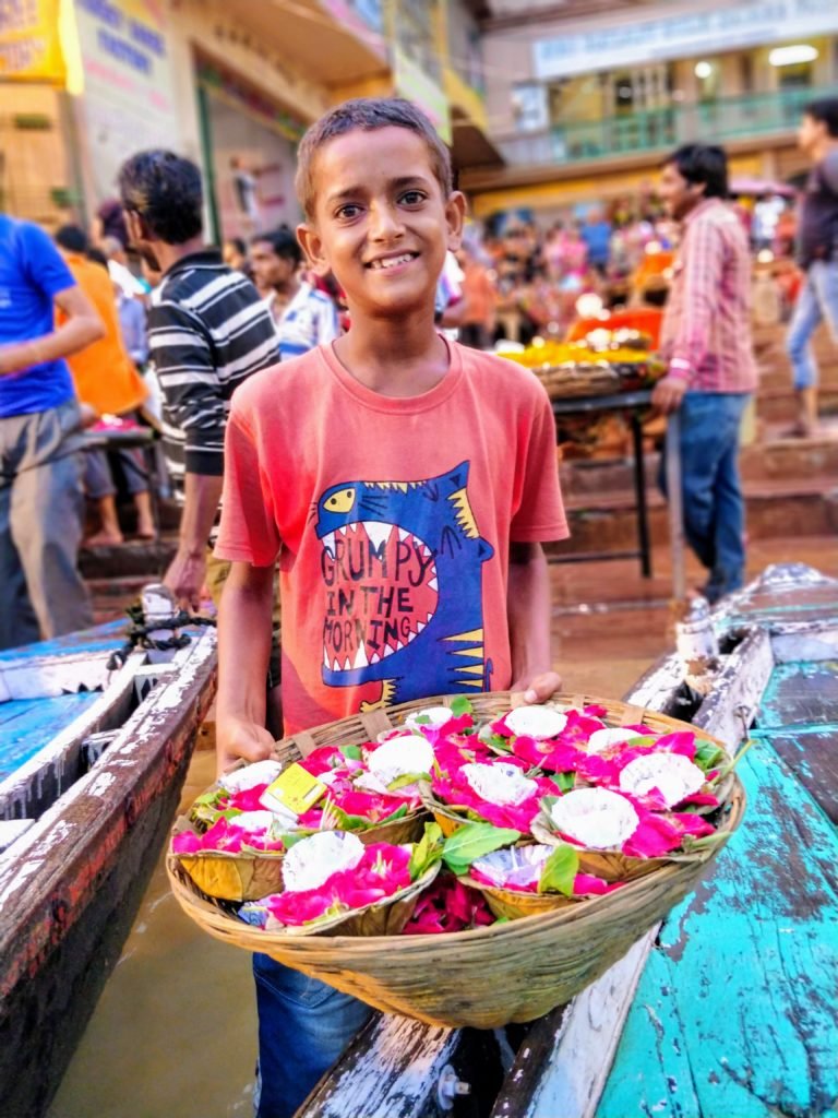 a flower boy selling flowers and diyas by the Dashashwamedh Ghat in Varanasi