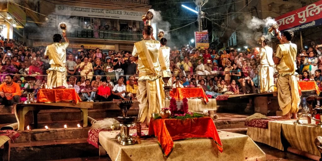 one of the stages of ganga aarti where the indian priests dressed in indian dhoti kurta attire offer incense sticks to the holy ganges