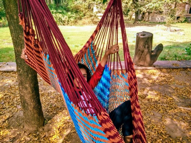 a child sitting on a red and blue hammock in Deo Bagh Gwalior Heritage Hotel Image