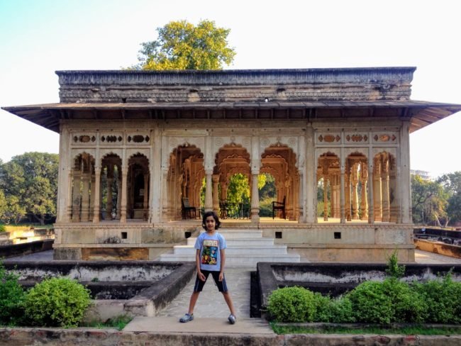 A boy sitting in front of the 17th century 36 arched doors pavilion in Neemrana's Deo Bagh Gwalior